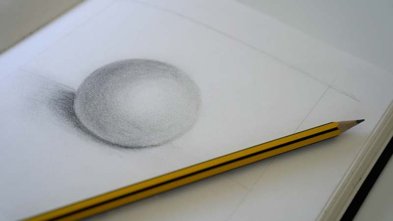 Hand sketching a detailed pencil drawing on textured paper with natural lighting